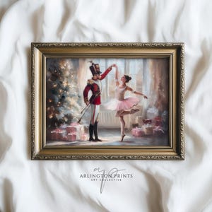 May include: Framed art print depicting a ballet dancer and a toy soldier in a Christmas scene. The soldier wears a red coat and tall hat, while the dancer is in a pink tutu. The print is in a gold frame, with the text "ARLINGTON PRINTS ART COLLECTIVE".
