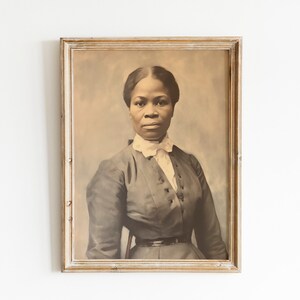 May include: Framed sepia-toned portrait of a woman in a dark dress with a white collar. The portrait is in a rectangular, distressed, light-colored wooden frame. The woman is facing forward, with a serious expression.