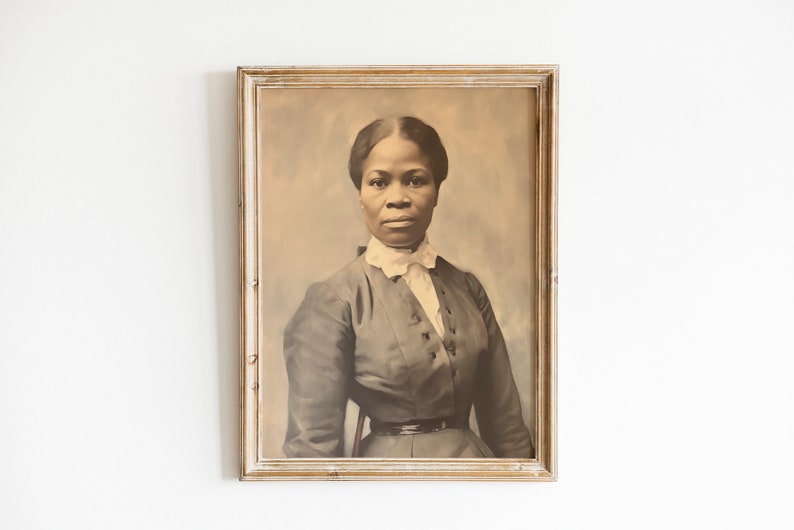 May include: Framed sepia-toned portrait of a woman in a dark dress with a white collar. The portrait is in a rectangular, distressed, light-colored wooden frame. The woman is facing forward, with a serious expression.