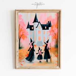 May include: A framed art print featuring a painting of three figures in black witch costumes with pink ribbons, walking toward a large white mansion. The scene is set against a backdrop of orange and pink autumn trees, with an orange pumpkin bucket.
