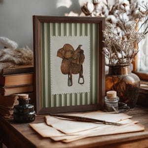 Printed Western wall art featuring a detailed illustration of a vintage leather cowboy saddle with stirrups, displayed on textured parchment-style paper with a striped green and cream background. Ideal for rustic home decor, ranch houses, barns, or cowboy-themed rooms. This artwork evokes classic Western heritage and equestrian charm, making it a perfect printed piece for lovers of country and cowboy style.