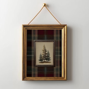 May include: A framed artwork featuring a painting of three evergreen trees. The artwork is set within a gold-colored frame, and is hung by a gold-colored cord. The background is a plaid pattern in shades of red, green, and brown.