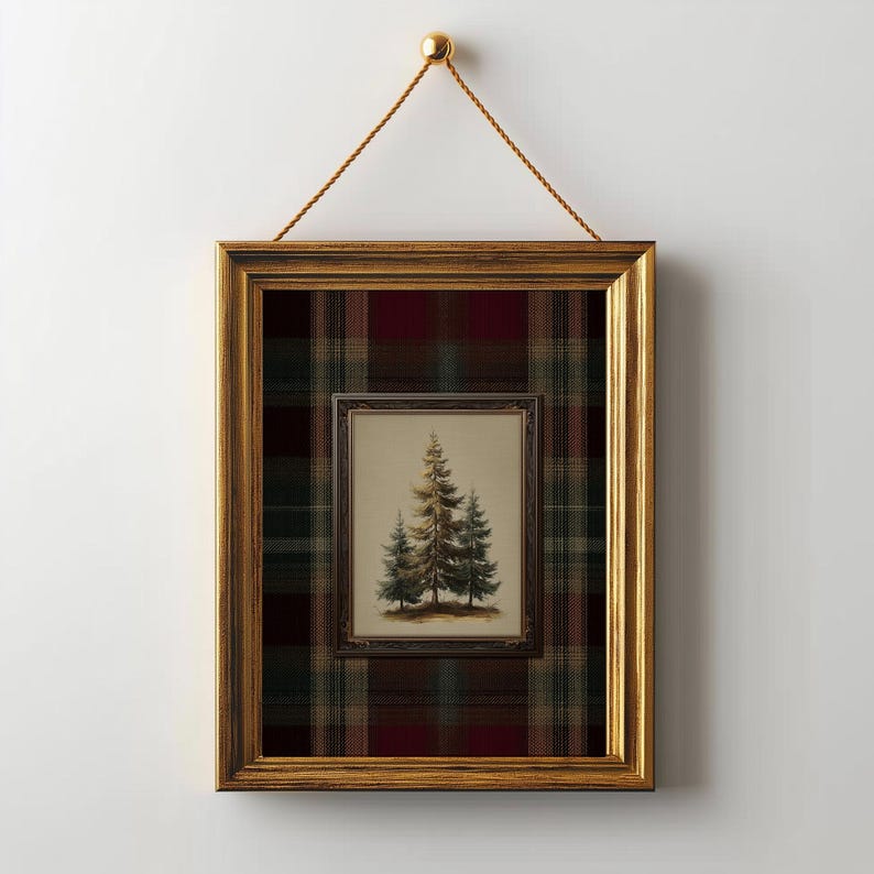 May include: A framed artwork featuring a painting of three evergreen trees. The artwork is set within a gold-colored frame, and is hung by a gold-colored cord. The background is a plaid pattern in shades of red, green, and brown.