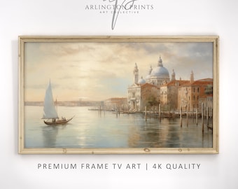May include: A framed painting of a cityscape with a sailboat in the foreground. The city is built on a canal with buildings and a church in the background. The sky is a soft orange and pink.