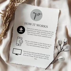 May include: A white sheet of paper with black text explaining how to download and upload images to a Samsung Frame TV using the SmartThings app. The text includes instructions to create a folder named "Frame TV Art" on your phone and save the downloaded image there. The image also shows icons of a download arrow, a phone with a checkmark, and a television.