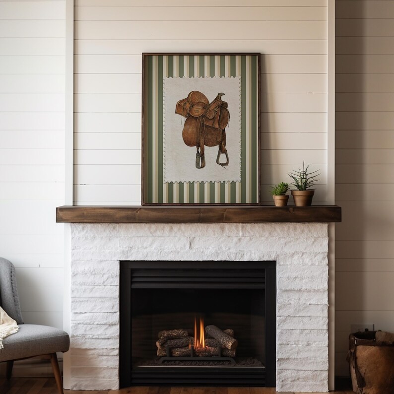 Printed Western wall art featuring a detailed illustration of a vintage leather cowboy saddle with stirrups, displayed on textured parchment-style paper with a striped green and cream background. Ideal for rustic home decor, ranch houses, barns, or cowboy-themed rooms. This artwork evokes classic Western heritage and equestrian charm, making it a perfect printed piece for lovers of country and cowboy style.