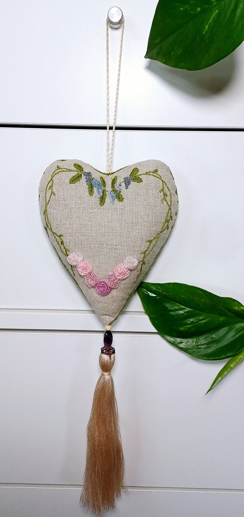 Hand embroidered linen sachet with tassel and hanging loop filled with lavender hanged on drawer knob