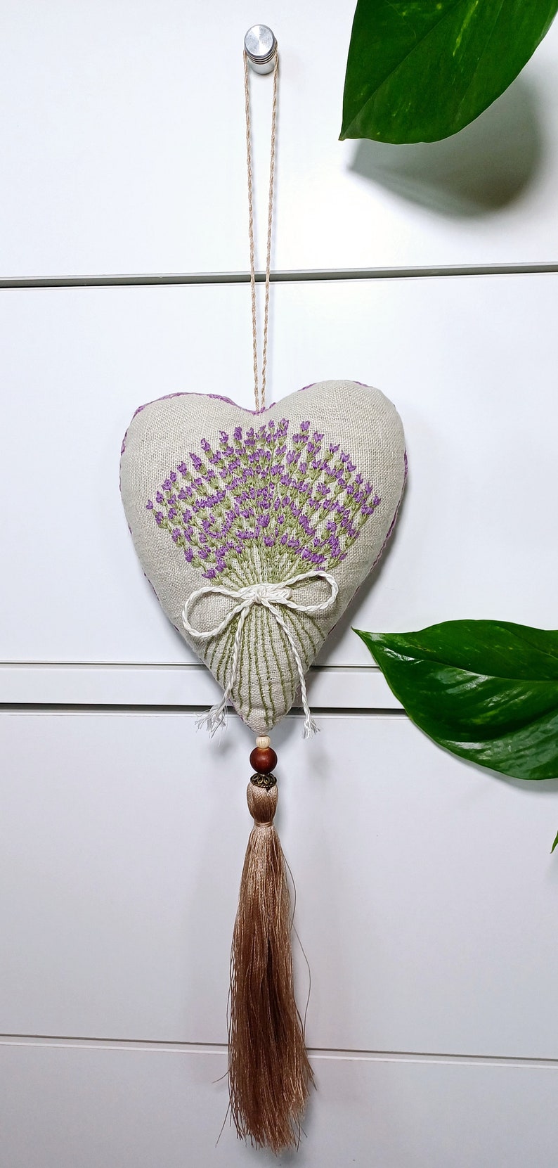 Handmade hand embroidered heart shaped linen sachet with hanging loop and tassel filled with lavender. Hung on drawer knob. Embroidered lavenders.