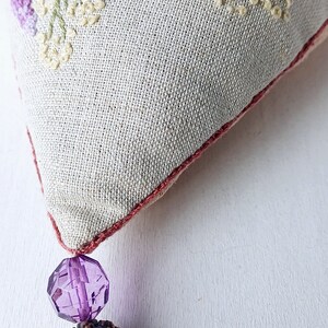 Handmade embroidered linen heart shaped home decor sachet, with hanging loop and tassel.