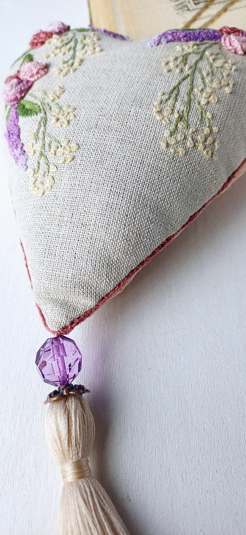Handmade embroidered linen heart shaped home decor sachet, with hanging loop and tassel.