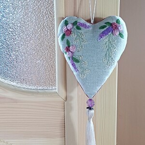 Handmade embroidered linen heart shaped home decor sachet, with hanging loop and tassel. Hung on a door hanger.