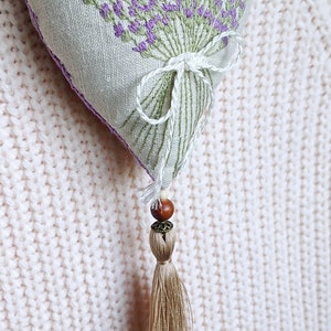 Handmade hand embroidered heart shaped linen sachet with hanging loop and tassel filled with lavender. Hung on cloth hanger. Embroidered lavenders.