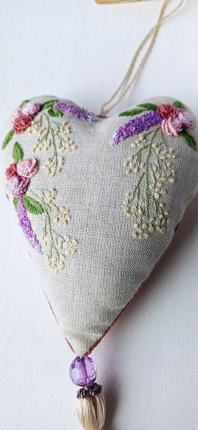 Handmade embroidered linen heart shaped home decor sachet, with hanging loop and tassel.