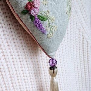 Handmade embroidered linen heart shaped home decor sachet, with hanging loop and tassel. Hung on a clothes hanger.