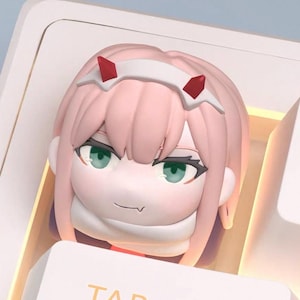 May include: A custom keycap featuring a pink anime character with green eyes and red horns. The keycap is designed to fit on a keyboard and has a detailed, sculpted appearance. The keycap is a light pink color.