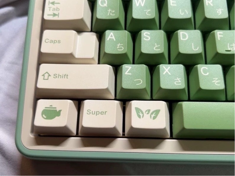 May include: A green and white keyboard with Japanese characters on the keys. The keys have various symbols, including a teapot, a leaf, and the word "Super".