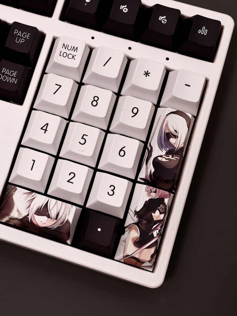 K&ouml;nnte beinhalten: Eine wei&szlig;e mechanische Tastatur mit schwarzen Tasten und benutzerdefinierten Tastenkappen mit Anime-Charakteren. Die Tastenkappen zeigen Bilder von Charakteren in Schwarz-Wei&szlig;-Kleidung und lila Haaren. Die Tastatur verf&uuml;gt &uuml;ber einen Nummernblock mit Tasten von 1 bis 9, 0, *, /, -, und .