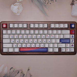 May include: A full-size keyboard with a wooden frame and white keys. The keyboard has a Korean language layout with a red, white, and blue accent strip. The space bar key has the Korean text "안녕하세요" which translates to "Hello" in English.