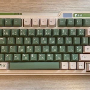 May include: A white and green keyboard with Japanese characters and the text "Kzzi" and "クリーム抹茶" printed on the keys. The keyboard has a cream-coloured frame and green accents.