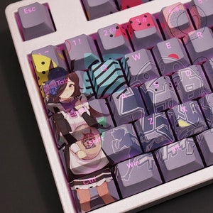 Może przedstawiać: Biała mechaniczna klawiatura z niestandardowymi klawiszami z kolorowymi wzorami i ilustracjami postaci z anime. Klawisze zawierają różne wzory, takie jak paski, kropki i kształty geometryczne. Klawiatura ma biało-fioletowy schemat kolorystyczny.