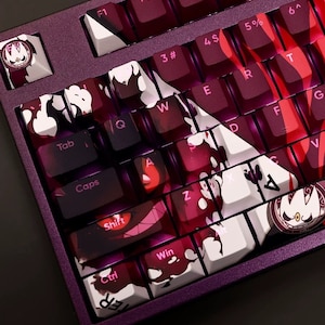 May include: A custom keyboard with a dark purple case and white keycaps. The keycaps feature a black and white graphic design with a red and white colour scheme. The keyboard has a variety of keys, including F1, F2, F3, F4, Tab, Caps, Shift, Ctrl, Win, and more.