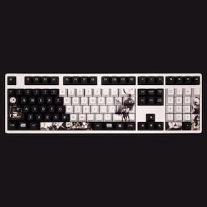 K&ouml;nnte beinhalten: Eine wei&szlig;e und schwarze mechanische Tastatur mit einem benutzerdefinierten Tastenkappen-Set mit einem Schwarzwei&szlig;-Anime-Design. Die Tastatur hat ein vollst&auml;ndiges Layout mit einem Nummernblock und Funktionstasten. Die Tastenkappen haben eine Vielzahl von Zeichen und Symbolen, die darauf gedruckt sind.