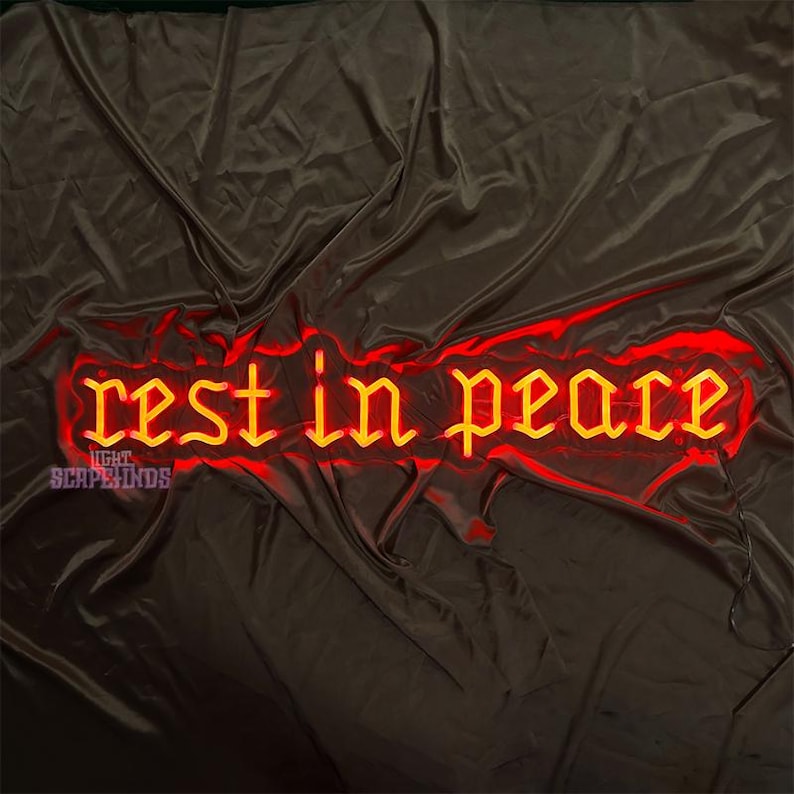 K&ouml;nnte beinhalten: Ein Neon-Schild mit den Worten "Ruhe in Frieden" in einer gotischen Schriftart. Das Schild leuchtet in einem leuchtenden Gelb und ist vor einem dunkelroten Hintergrund platziert.