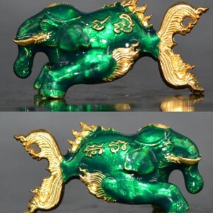 Può includere: Figurina verde e dorata di una creatura mitologica con una lunga coda e caratteristiche simili a quelle di un elefante. La creatura sta correndo e ha dettagli intricati.