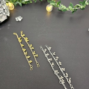 May include: Two pairs of delicate chains with small, round beads hanging from each link. One pair is gold and the other is silver.