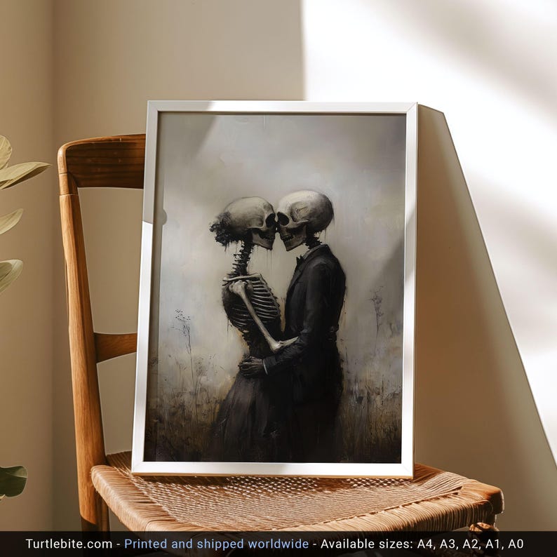 May include: A framed wall art print featuring a dark, atmospheric illustration of two skeletons embracing. One skeleton wears a dark dress and the other a dark suit. The background is a muted, hazy landscape in shades of gray, beige, and brown.