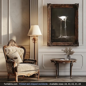 Op de afbeelding: Een ingelijste print van een witte kat met lange, dunne poten die in een plas water staat. De print is in een gouden lijst en hangt aan een muur in een kamer met een stoel en een tafel.