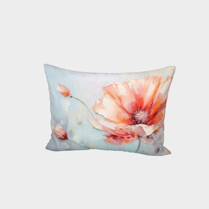 May include: A decorative pillow with a floral design featuring a large, orange poppy flower with a pink center and two smaller buds. The background is a light blue watercolor wash.