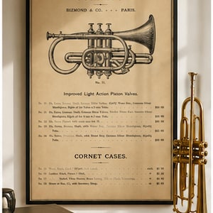 Op de afbeelding: Een ingelijste print in vintage-stijl met een technische illustratie van een kornet met de tekst CORNETS, BIZMOND & CO. PARIS, en Improved Light Action Piston Valves, tentoongesteld naast een koperen kornet, twee boeken en een notitieboek.