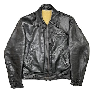 Peut inclure: Veste en cuir noir avec un col et une fermeture éclair intégrale. La veste a deux poches avant et une petite poche poitrine. La doublure intérieure est de couleur beige clair. Aspect vintage.