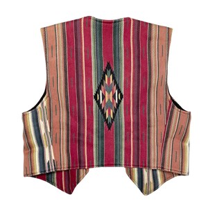 Peut inclure: Un gilet coloré avec un motif du Sud-Ouest. Le gilet présente des rayures verticales rouges, oranges, vertes et crème, avec un motif en forme de losange au centre. Le gilet a une doublure noire et une coupe classique.