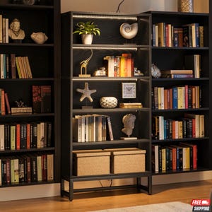 Könnte beinhalten: Ein dunkelgraues Bücherregal mit mehreren Regalböden, die mit Büchern, Dekorationsartikeln und zwei gewebten Aufbewahrungsboxen gefüllt sind. Die Regale sind mit LED-Leuchten beleuchtet. Das Bücherregal ist Teil eines Dreiersets.