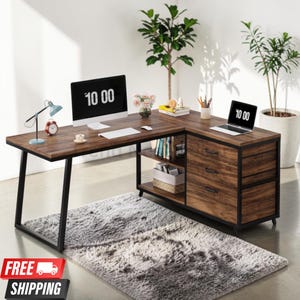 May include: An L-shaped desk with a dark wood grain finish and a black metal frame. The desk features three drawers with black handles, an open storage shelf, and a wide workspace surface. The desktop holds a computer monitor and a laptop.