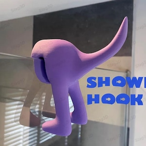 Può includere: Ganci doccia a forma di dinosauro stampati in 3D di colore viola. Il gancio è progettato per assomigliare a un dinosauro in piedi sulle zampe posteriori con la coda arrotolata. Il testo "SHOWER HOOK" è stampato in blu su sfondo bianco.