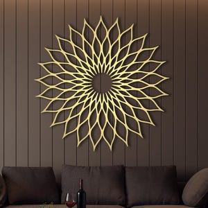May include: A gold-coloured, geometric wall art piece in a floral design hangs above a brown sectional sofa. The living room has a modern aesthetic with dark brown walls and light brown flooring. A small table holds a bottle of wine and glasses.