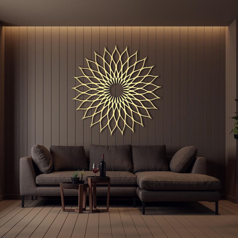 May include: A gold-coloured, geometric wall art piece in a floral design hangs above a brown sectional sofa. The living room has a modern aesthetic with dark brown walls and light brown flooring. A small table holds a bottle of wine and glasses.