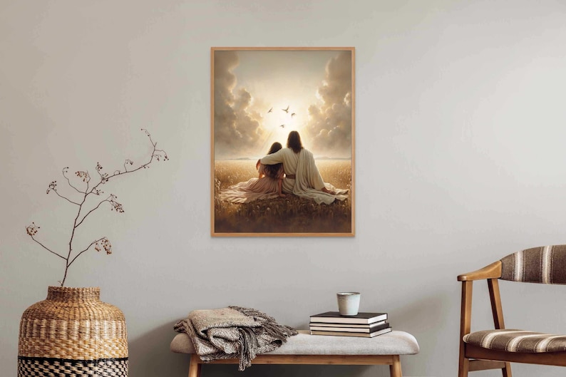 May include: A framed print depicts two figures embracing, seated in a field, with a bright light and birds in the sky. The artwork is in a wooden frame and hangs on a light gray wall. A decorative vase and bench are in the foreground.