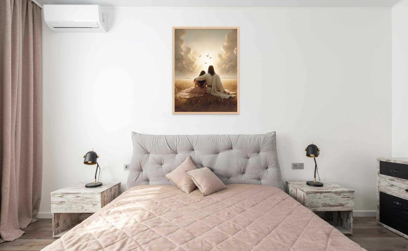 May include: A framed print depicting two figures seated together, bathed in warm sunlight. The artwork features soft colors and a serene landscape, evoking a sense of peace and comfort. The print is displayed above a bed with a tufted headboard.