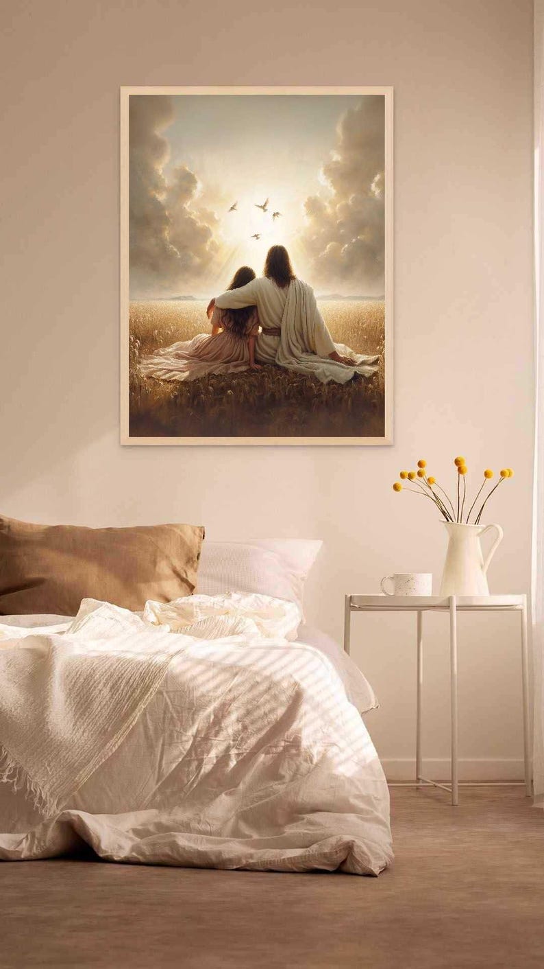 May include: A framed print depicts two figures embracing in a field, with a bright sky and birds overhead. The artwork is in a white frame and is displayed above a bed with white bedding. A small white table holds a vase of yellow flowers.