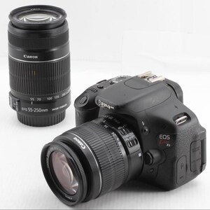 May include: A black Canon EOS Xs digital camera with a lens attached, and a separate black Canon lens. The attached lens has settings from 18-55mm. The separate lens has settings from 55-250mm.