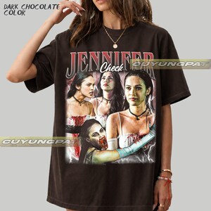K&ouml;nnte beinhalten: Dunkel schokoladenfarbenes T-Shirt mit einer Grafik einer Frau und dem Text "JENNIFER Check" im Vintage-Stil. Die Grafik enth&auml;lt mehrere Bilder der Frau mit einem Horror-Thema. Das Shirt hat einen Rundhalsausschnitt und kurze &Auml;rmel.