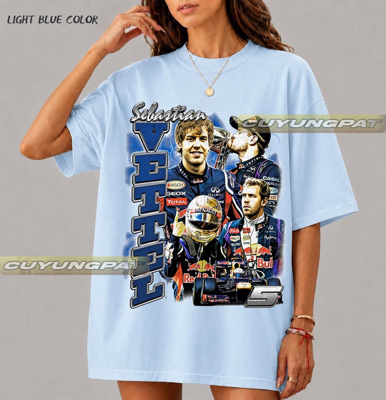 May include: A light blue t-shirt featuring a graphic print of Formula 1 driver Sebastian Vettel. The design includes multiple images of the driver, a racing helmet, a race car, the text "Sebastian Vettel," and the number "5" in a bold font.