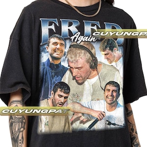 May include: Black t-shirt with a graphic print of four men. The text "FRED Again" is printed in blue on the shirt.