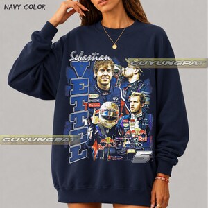 May include: A navy blue crewneck sweatshirt featuring a graphic print of Formula 1 driver Sebastian Vettel. The design includes multiple images of the driver in racing gear, the text "Sebastian VETTEL", the number "5", and "NAVY COLOR" text.