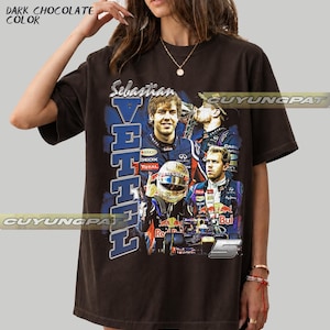 May include: A dark chocolate colored t-shirt featuring a graphic print of Formula One driver Sebastian Vettel. The design includes multiple images of the driver, the text "Sebastian VETTEL", and the number "5" in a bold, blue-toned collage style.