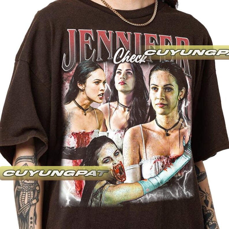 K&ouml;nnte beinhalten: Dunkelbraunes T-Shirt mit einer Grafik einer Frau und dem Text "JENNIFER Check". Die Grafik enth&auml;lt mehrere Bilder der Frau mit einem Horror-Thema. Das Shirt hat kurze &Auml;rmel und einen Rundhalsausschnitt.